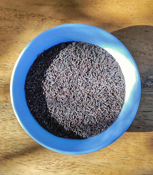 A bowl of Kala Jeera, also known as Black Cumin, displayed on a wooden surface.
