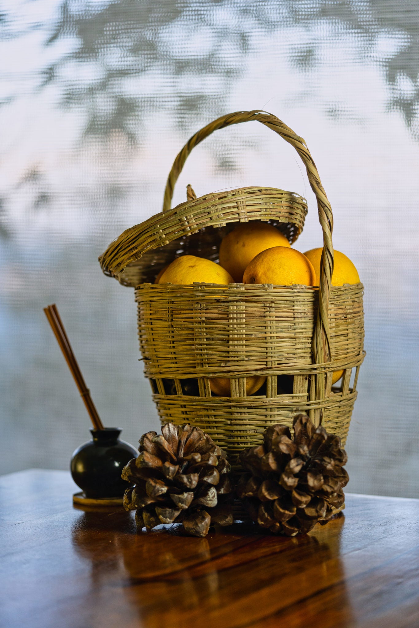 Shopping basket for veggies with lid and handle, containing lemons on a table